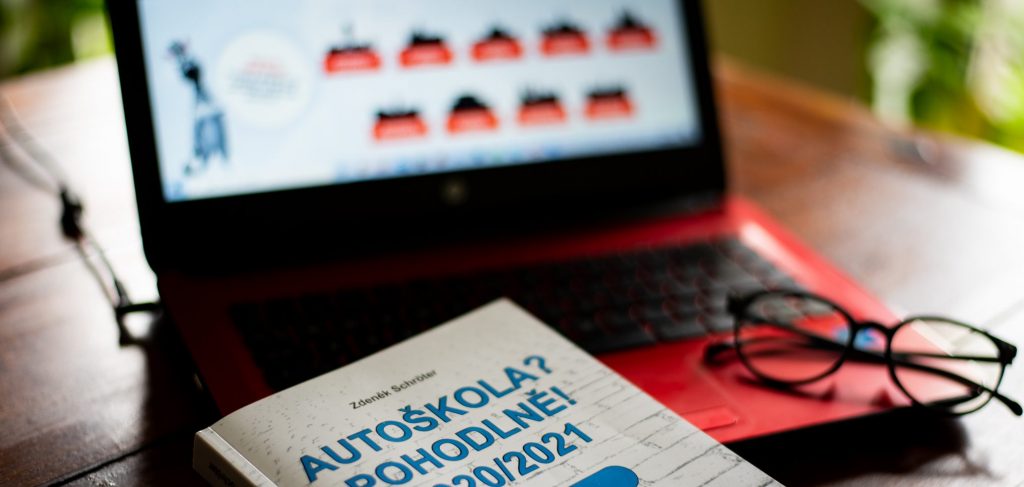 Učební materiály a testy autoškoly na stole.
