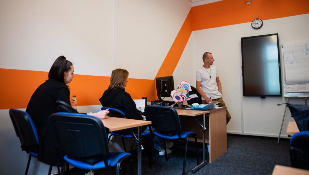 Učebna autoškoly s lavicemi a studenty.