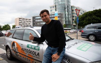 Lektor stojící u výcvikového vozu autoškoly.