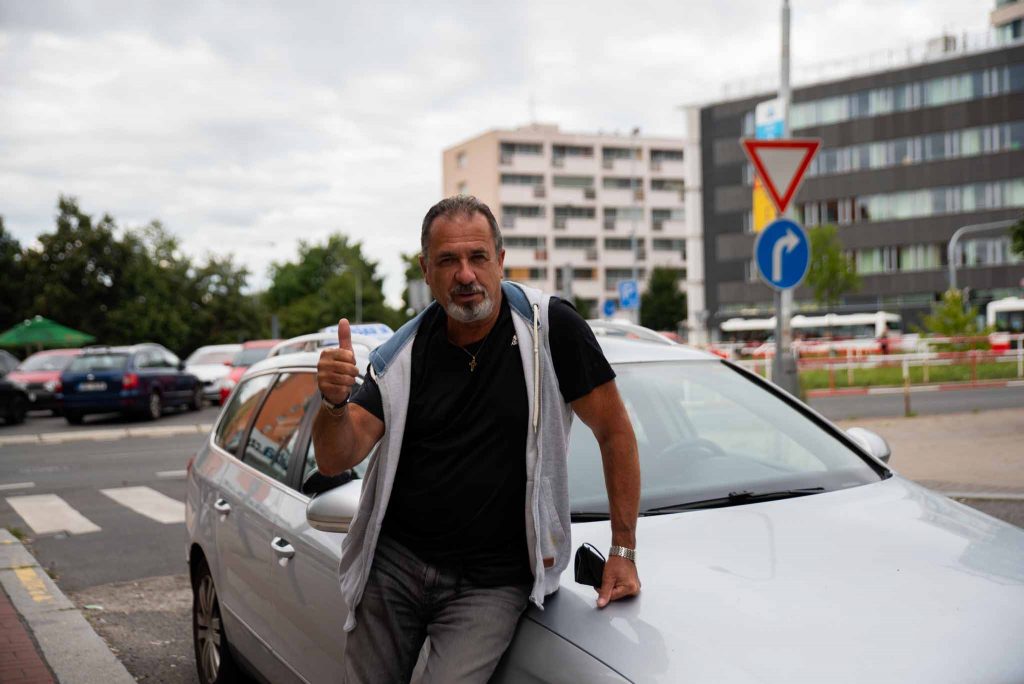 Lektor stojící u výcvikového vozu autoškoly.