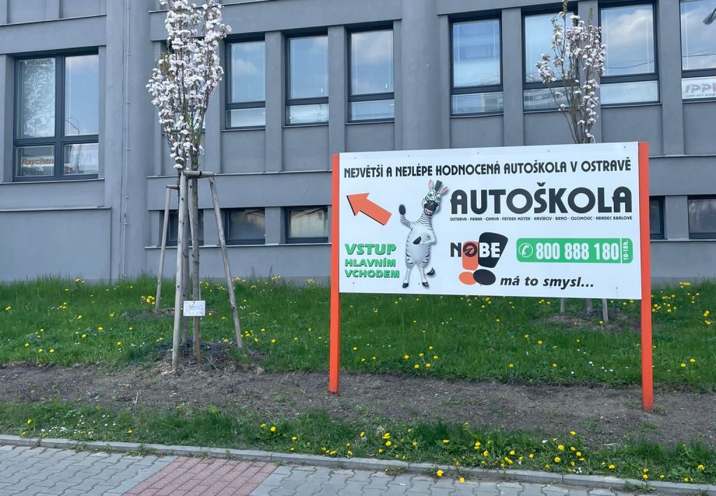 Pobočka autoškoly s reklamním poutačem na budově.