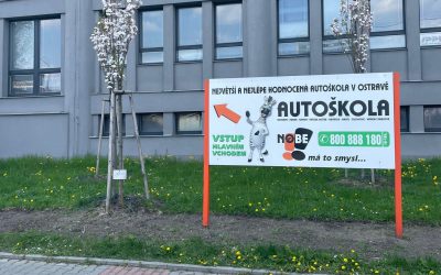 Pobočka autoškoly s reklamním poutačem na budově.