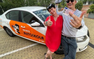 Pár stojící u oranžového polepeného vozu autoškoly.