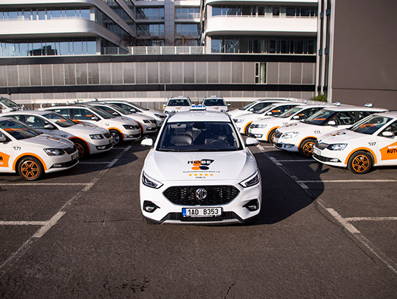 Řada výcvikových vozů autoškoly na parkovišti.